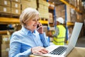 Senior woman manager with smartphone and man worker working in a warehouse. Royalty Free Stock Photo