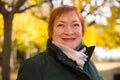 Woman with maple leaves walks in autumn park