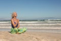 Senior woman meditating while sitting on shore against clear sky Royalty Free Stock Photo