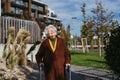 Senior woman with a mobility walker walking on city streets during autumn day, enjoying the beautiful sunny weather