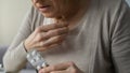 Senior woman nervously taking medicine, labored breathing symptom, closeup