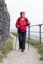 Senior woman Nordic walking on rocky trail