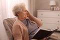 Senior woman with notebook at home. Age-related memory impairment