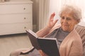 Senior woman with notebook at home, space for text. Age-related memory impairment