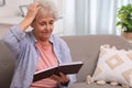 Senior woman with notebook at home, space for text. Age-related memory impairment