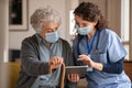 Senior woman and nurse using digital tablet at home during consult Royalty Free Stock Photo