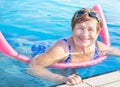 Senior woman (over age of 50) doing aqua fitness with swim noodles in swimming pool. Royalty Free Stock Photo