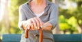 Senior woman, park and hand with cane in nature for mobility support, healthcare and balance. Sunshine, garden and