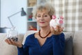 Senior woman on pension weighing containers with saved money for future