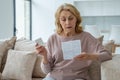Senior woman with pills reads the instructions at home sitting on the couch Royalty Free Stock Photo