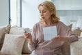 Senior woman with pills reads the instructions at home sitting on the couch Royalty Free Stock Photo