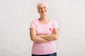 Senior Woman In Pink Breast Cancer T-Shirt Standing Over White Wall Royalty Free Stock Photo