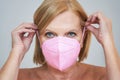 Senior woman in pink mask posing over gray background