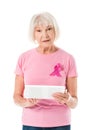 senior woman in pink t-shirt with breast cancer awareness ribbon holding digital tablet and looking at camera Royalty Free Stock Photo