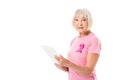 senior woman in pink t-shirt with breast cancer awareness ribbon using digital tablet and looking at camera Royalty Free Stock Photo