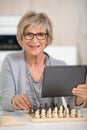 senior woman playing chess and holding tablet Royalty Free Stock Photo