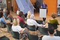 Senior Woman At Podium Chairing Neighborhood Meeting In Community Centre Royalty Free Stock Photo