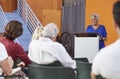 Senior Woman At Podium Chairing Neighborhood Meeting In Community Centre Royalty Free Stock Photo