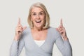 Senior woman pointing fingers up feels excited studio head shot Royalty Free Stock Photo