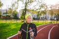 Senior woman practicing nordic walking at city stadium and stopped to quench thirst, drink water from bottle. Age, maturity, Royalty Free Stock Photo