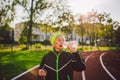 Senior woman practicing nordic walking at city stadium and stopped to quench thirst, drink water from bottle. Age, maturity, Royalty Free Stock Photo