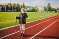 Senior woman practicing nordic walking at city stadium and stopped to quench thirst, drink water from bottle. Age, maturity, Royalty Free Stock Photo