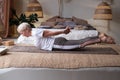 Senior woman practicing yoga at home indoor, doing Salabhasana or Locust pose