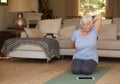 Senior woman practising yoga at home with a digital tablet