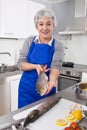 Senior woman preparing fish in kitchen Royalty Free Stock Photo