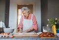 Senior woman preparing traditional easter meals for family, kneading dough for easter cross buns. Recreating family