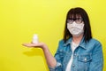 Senior Woman in Protective Face Mask Keeps Hand Pills Jar on Yellow Background