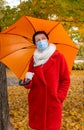 Senior woman protective medical mask autumn park age middle 50 plus umbrella red orange Royalty Free Stock Photo