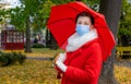 Senior woman protective medical mask autumn park age middle 50 plus umbrella red orange Royalty Free Stock Photo