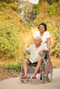 Senior woman pushing her disabled hasband on wheelchair