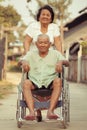 Senior woman pushing her disabled hasband on wheelchair