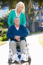 Senior Woman Pushing Husband In Wheelchair Royalty Free Stock Photo