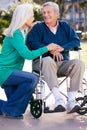 Senior Woman Pushing Husband In Wheelchair Royalty Free Stock Photo