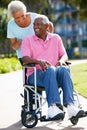 Senior Woman Pushing Husband In Wheelchair Royalty Free Stock Photo