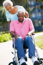 Senior Woman Pushing Unhappy Husband In Wheelchair