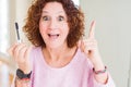 Senior woman putting mascara on eyelashes surprised with an idea or question pointing finger with happy face, number one Royalty Free Stock Photo