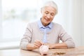 Senior woman putting money to piggy bank at home Royalty Free Stock Photo