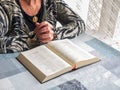Senior woman reading bible with gold medallion of virgin mary Royalty Free Stock Photo