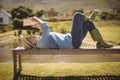 Senior woman reading a book while lying on the bench in the park Royalty Free Stock Photo