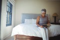 Senior woman reading book while sitting on bed in the bed room Royalty Free Stock Photo