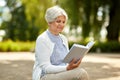 Senior woman reading book at summer park