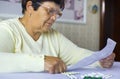 Senior woman reading information sheet of prescribed medicine sitting at table at home