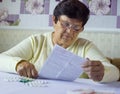 Senior woman reading information sheet of prescribed medicine sitting at table at home