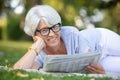 senior woman reading newspaper laying in grass Royalty Free Stock Photo