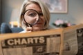 Senior woman reading newspaper with magnifying glass, unaware making funny facial expressions. Middle age retired female having Royalty Free Stock Photo