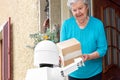Senior woman is receiving post from an futuristic robotic delivery service